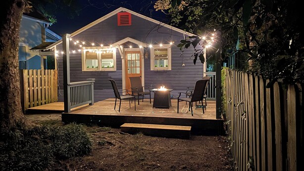 Eine Holzterrasse mit Feuerschale, umgeben von Stühlen und Lichterketten.