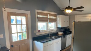 Eine kleine Küche mit Kühlschrank, Spüle und Deckenventilator.