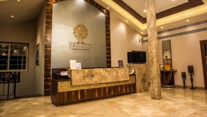 A reception desk with a logo, a TV, and a mirror. - Basilica Resort - Where Luxury Redefines (Panchgani)