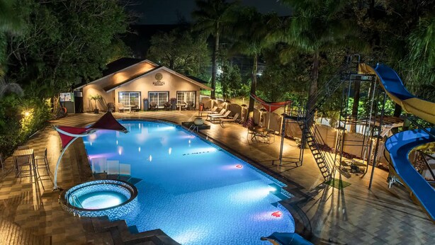 A swimming pool with a hot tub, lounge chairs, and a slide. - Basilica Resort - Where Luxury Redefines (Panchgani)