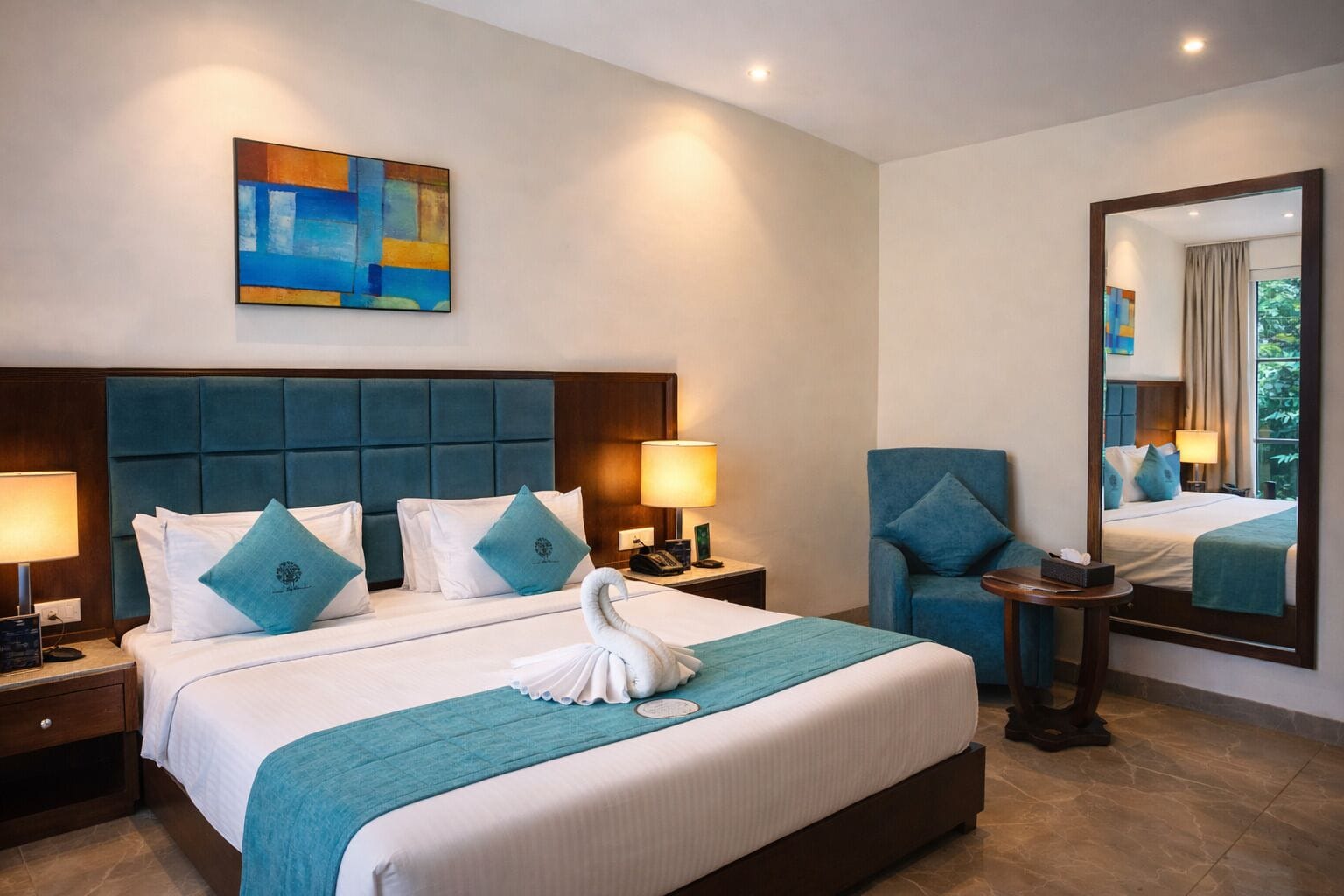A hotel room with a large bed, two bedside tables, a chair, a mirror, and a painting on the wall.