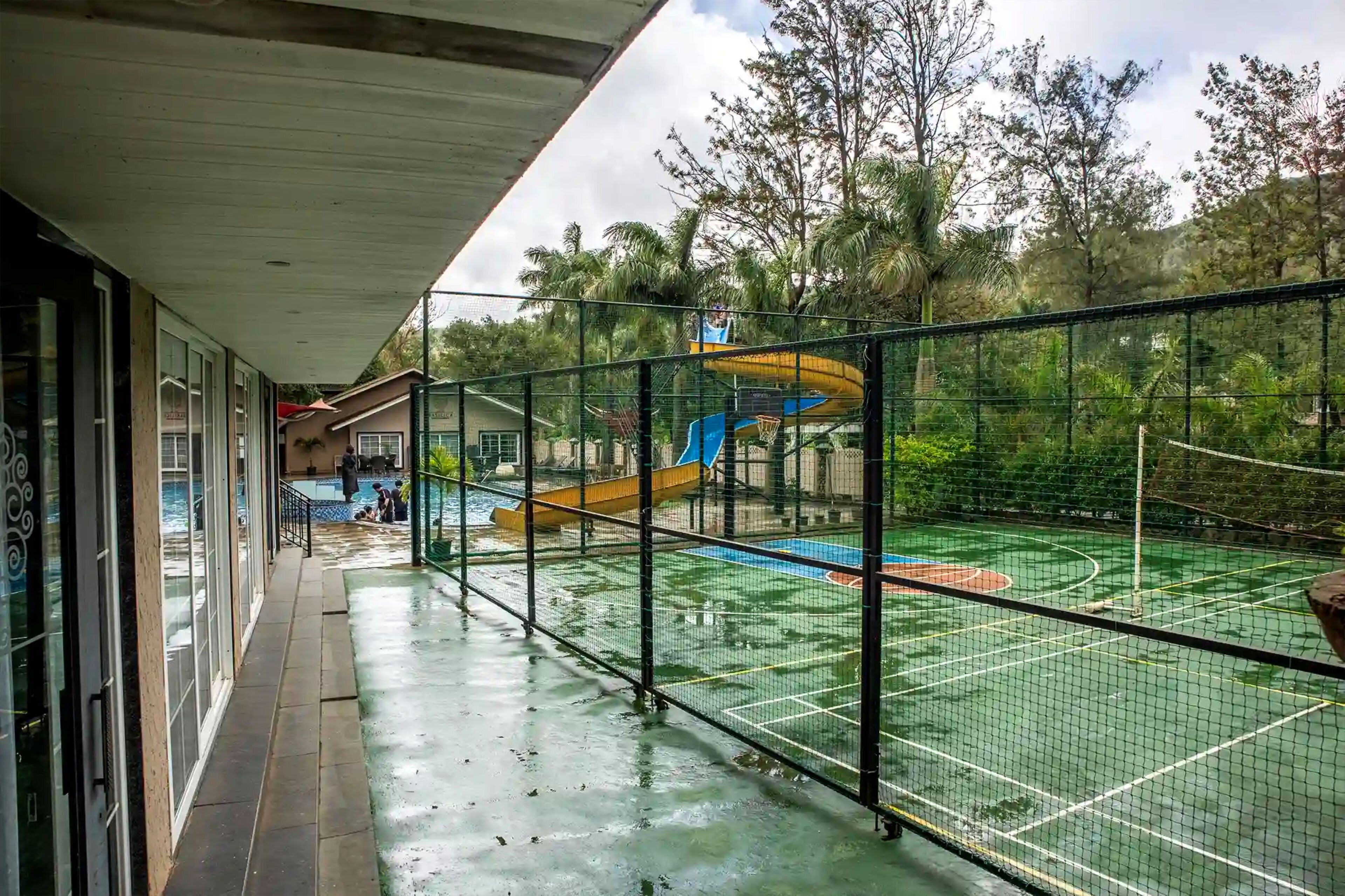 Instalación deportiva al aire libre con cancha de baloncesto, tobogán de agua y zona vallada.