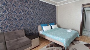 Un dormitorio con cama, sofá, armario y pared con diseño.