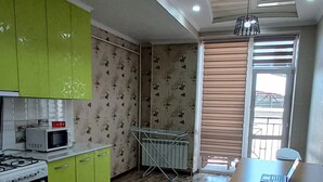 Una cocina moderna con gabinetes verdes, microondas, cocina a gas y una zona de comedor con mesa y sillas.