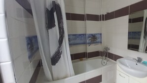 Un baño con bañera, lavamanos y espejo.