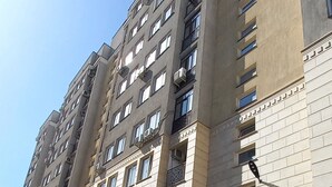Un edificio residencial de varios pisos con balcones, una entrada protegida por un portón y una acera bien cuidada.
