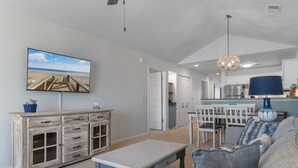 Un salón espacioso con televisor grande, comedor y cocina.