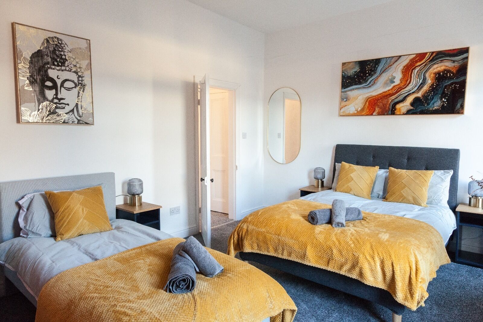 A hotel room with two beds, a large mirror, and artwork on the walls.