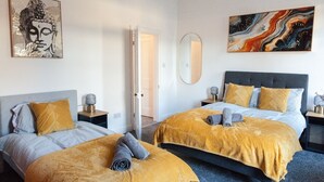 A hotel room with two beds, a large mirror, and artwork on the walls.