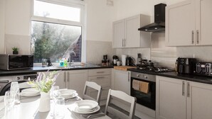 A modern kitchen with white cabinets, a black stove, and a dining area set for four.