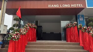 The entrance of Xiang Long Hotel with a red awning and floral decorations. - Xianglong Hotel (Luang Prabang)