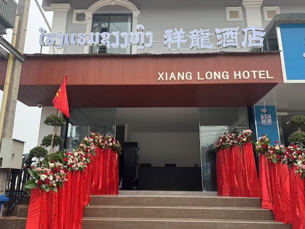 The entrance of Xiang Long Hotel with a red awning and floral decorations.