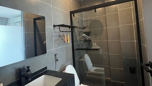A modern bathroom with a glass-enclosed shower, a large mirror, and a black countertop with a sink. - Xianglong Hotel (Luang Prabang)