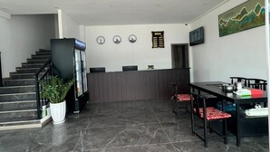 A spacious lobby with a marble floor, a staircase, a reception desk, and a dining area with chairs and a table. - Xianglong Hotel (Luang Prabang)