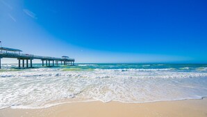 A beach with a pier extending into the ocean. - Emerald Skye 63 1 Bedroom Condo (Orange Beach)