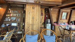 Acogedor dormitorio en ático con vigas de madera, un rincón de lectura elevado y una estantería llena de libros.