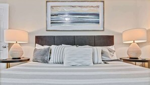 Un letto con una coperta a righe, due lampade sui comodini e un quadro incorniciato sopra.