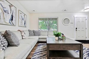 A living room with a sofa, coffee table, and artwork on the wall. - Stunning Private Home with Hot Tub (Boise)
