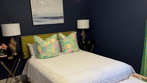 Un dormitorio con cama, lámparas de noche, un cabecero decorativo, una mesita de noche con lámpara, una lámpara de pie y un cuadro en la pared.