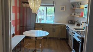 Una cocina moderna con una mesa redonda para comer, una lámpara colgante y suelo de madera.