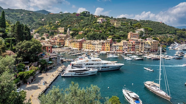 A marina with multiple yachts docked, surrounded by colorful buildings and lush greenery. - Charming Portofino 3-bed retreat (Portofino)