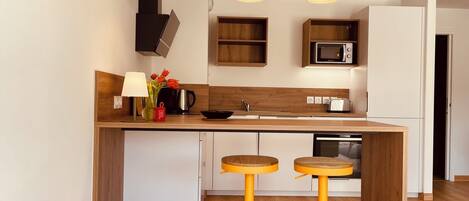 Una cocina moderna con armarios de madera, un microondas, un fregadero y dos taburetes amarillos.