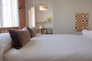 Une chambre à coucher avec un grand lit, une petite table avec des chaises, un luminaire suspendu et une décoration murale à carreaux.