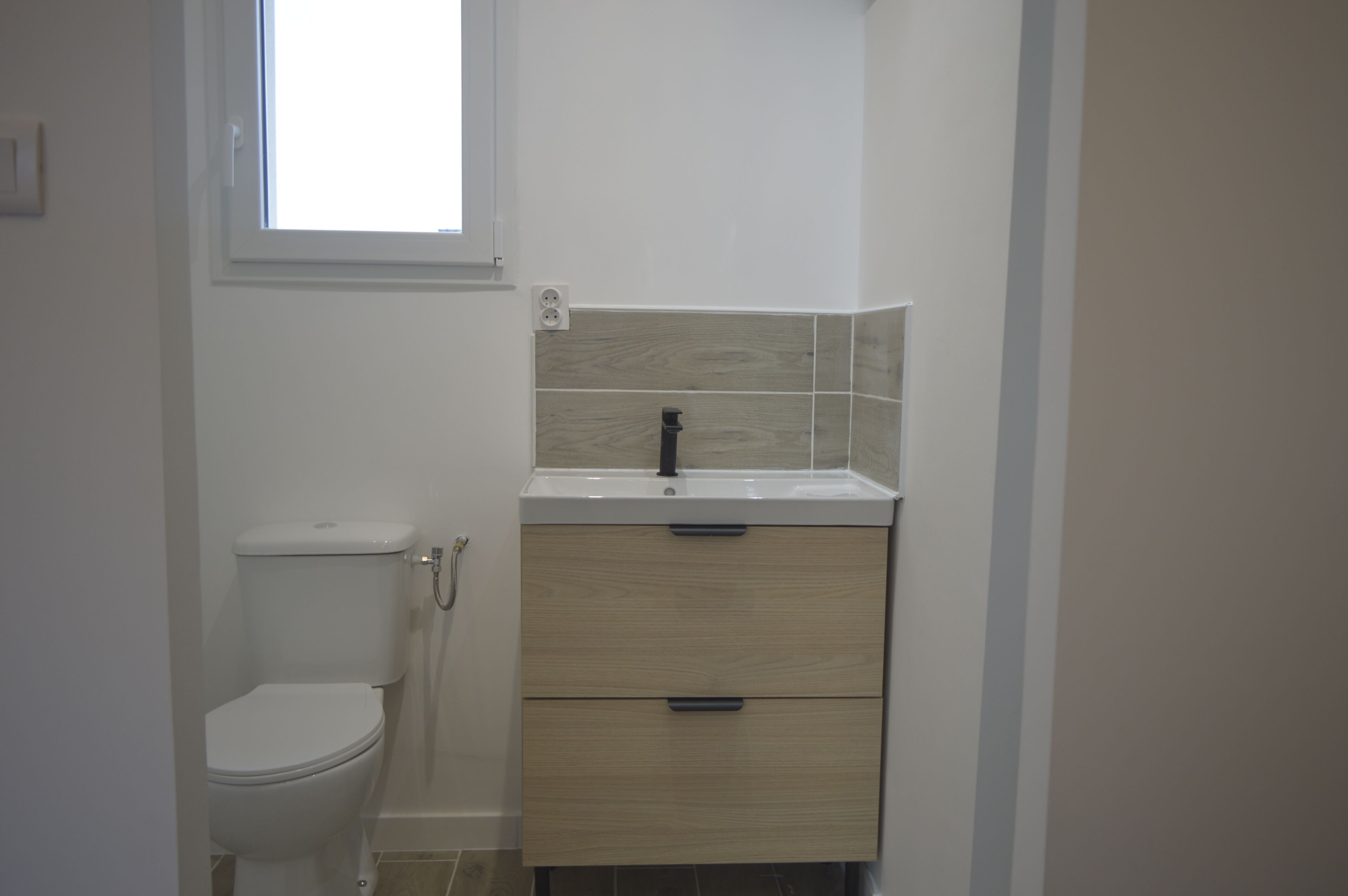 A small bathroom with a toilet, a sink, and a cabinet.
