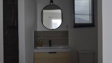 A bathroom with a round mirror, a sink with a wooden cabinet, and a toilet.
