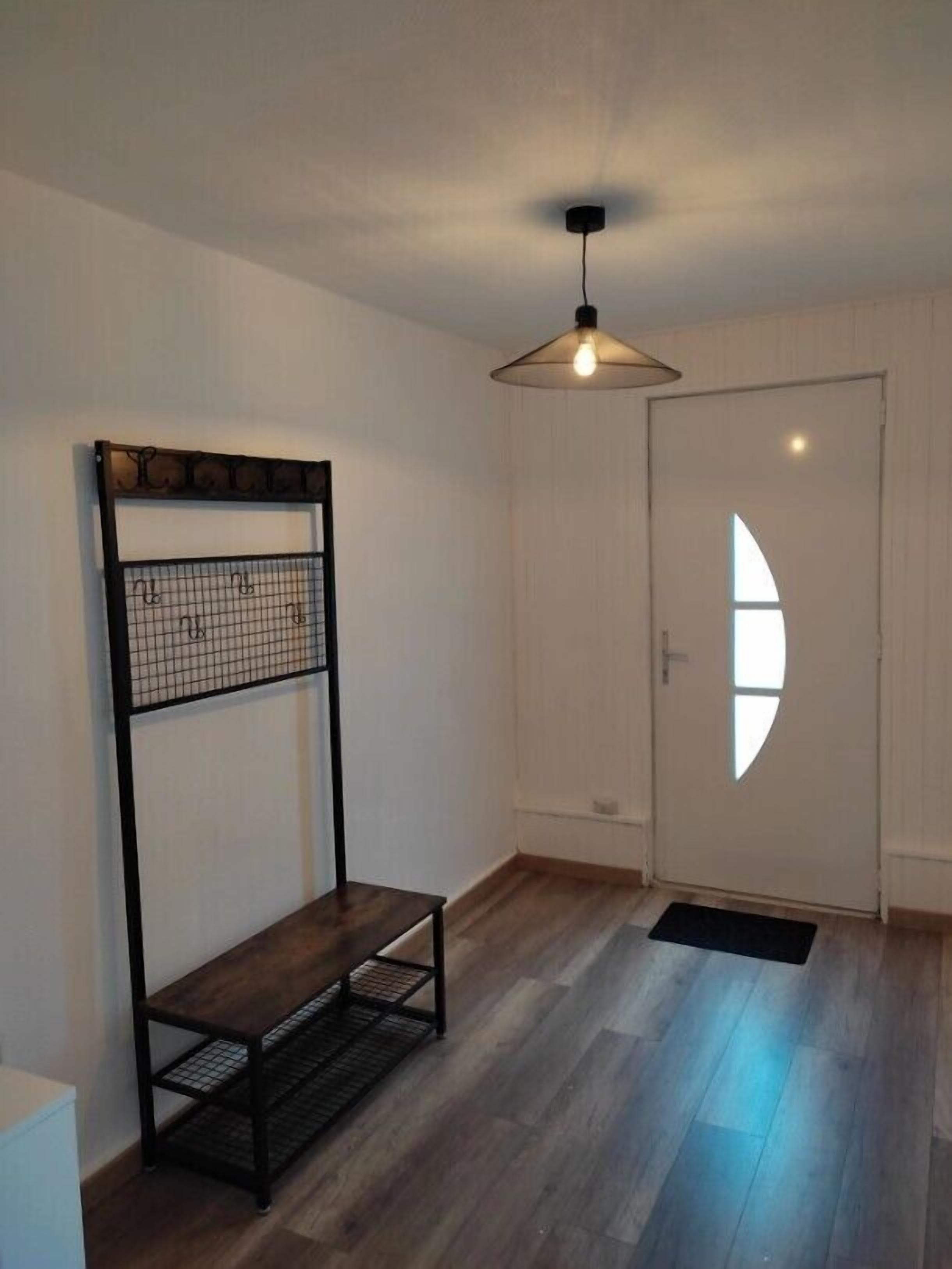 Una stanza con un letto a castello, un lampadario e un pavimento in legno, oltre a una porta con una finestra.