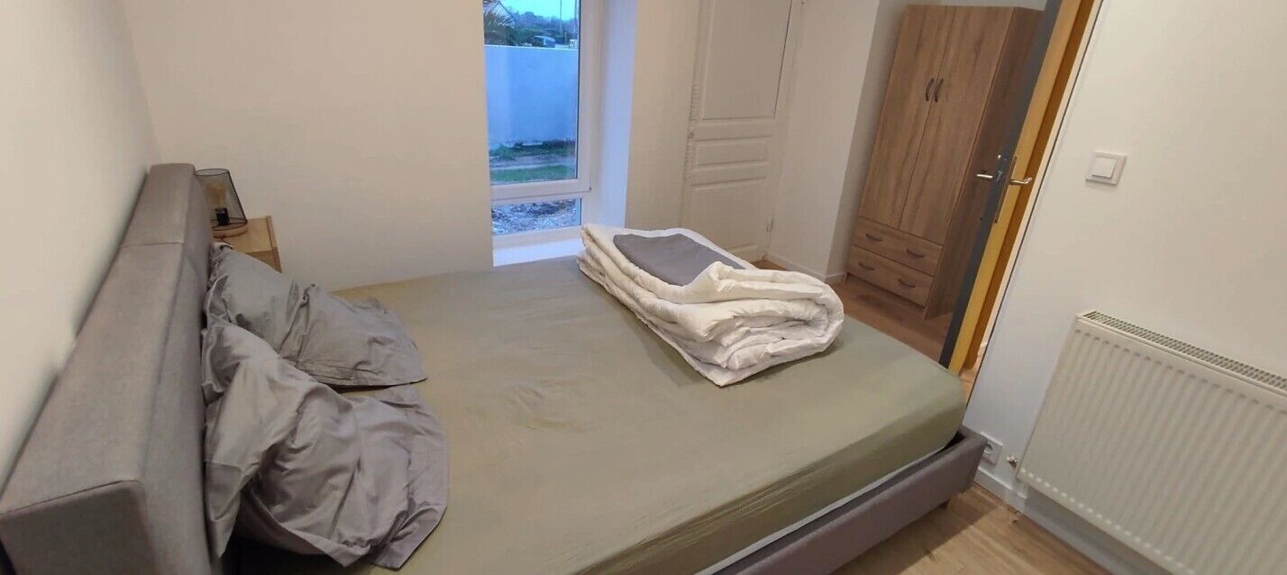 A bedroom with a single bed, a wardrobe, and a window.