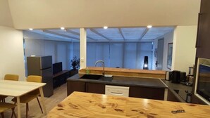 A compact kitchen with a central island, a dining area with a table and chairs, and a built-in oven. - Résidence des dunes (Landéda)