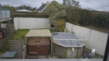 Un jardin avec un jacuzzi, une petite terrasse et une piscine.