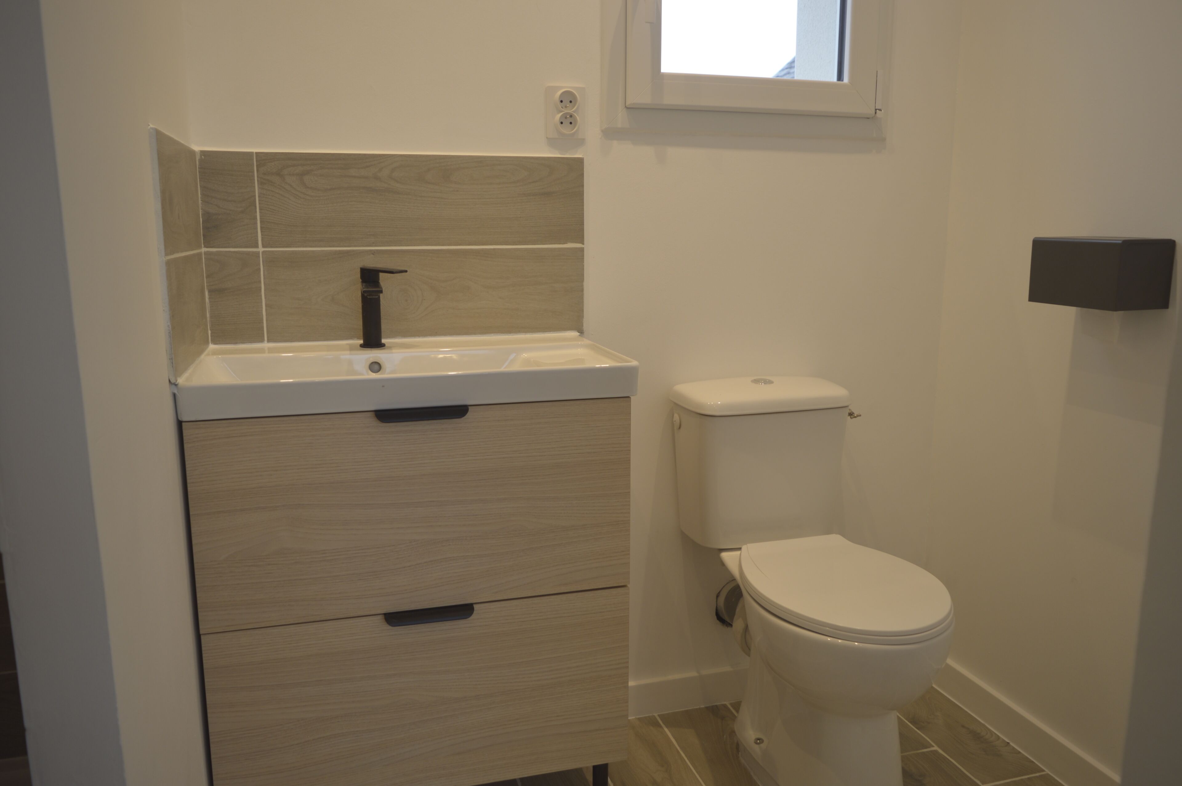 A bathroom with a toilet, a sink, and a cabinet.