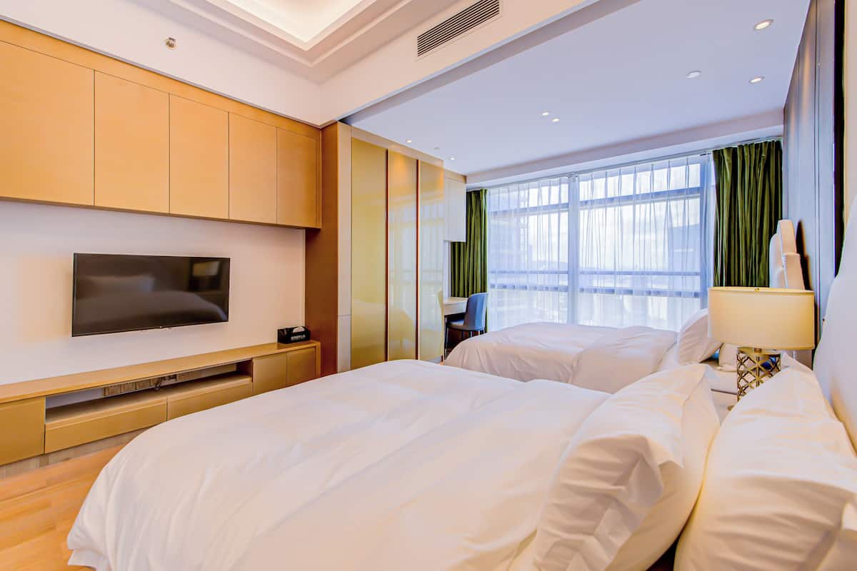 Una habitación de hotel con una cama grande, un televisor montado en la pared y un escritorio con una silla.