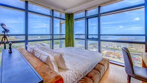 Une chambre d’hôtel située dans un immeuble de grande hauteur, équipée d’un grand lit, d’un bureau et d’un télescope.