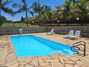 A swimming pool with lounge chairs and palm trees.