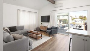 Una sala de estar moderna con un sofá, un sillón, una mesa de centro y un televisor.