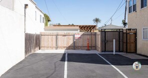 A gated driveway leading to a residential property with a wooden fence and a gated entrance.