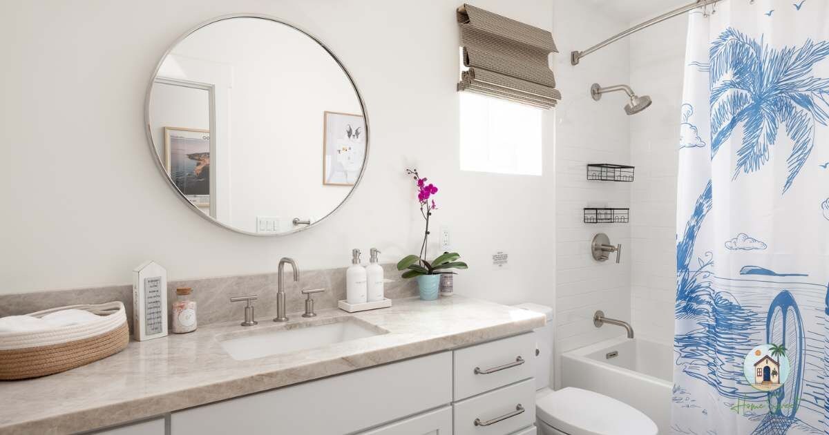 Un baño con un espejo redondo, un lavabo con dos grifos, una ducha con cabezal de ducha tipo lluvia y un perchero para toallas.