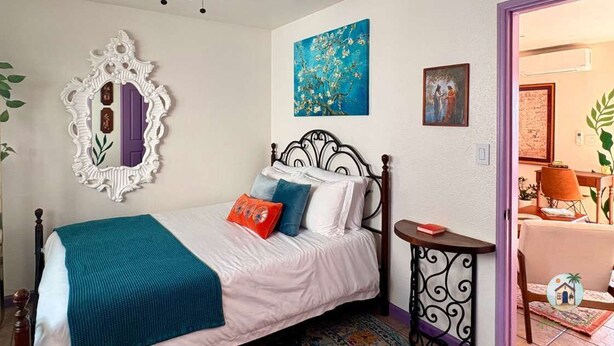 Quarto com cama, espelho e obras de arte nas paredes.