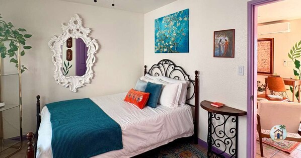 A bedroom with a bed, a mirror, and artwork on the walls.