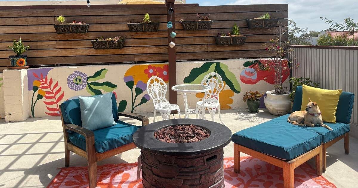 An outdoor patio with a fire pit, seating area, and a decorative wall with plants.