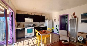 A compact kitchen with a microwave, stove, and sink, a dining table with chairs, and a small refrigerator.