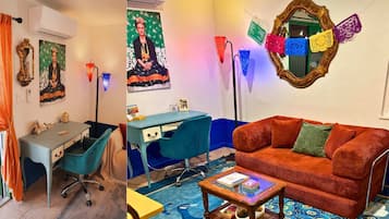 A room with a desk, a blue chair, a red sofa, and a coffee table.