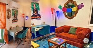 A room with a desk, a blue chair, a red sofa, and colorful decorations including a mirror and paper lanterns. - Casita Frida – Near Balboa Park (San Diego)