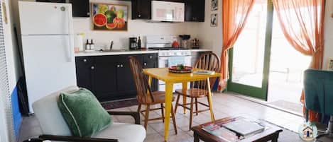 Un espacio habitable compacto con kitchenette, comedor y zona de estar.