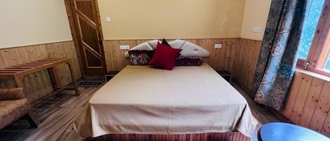 A bedroom with a bed, a bench, and a window with curtains.