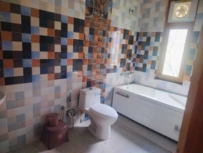 Ein Badezimmer mit gefliesten Wänden, einer Toilette, einem Waschbecken und einer Badewanne.