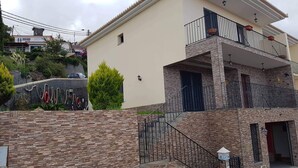 Un bâtiment à deux étages doté d’un balcon, d’un mur en pierre et d’un petit jardin.